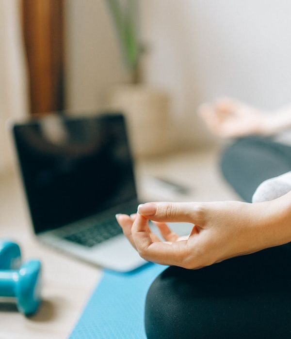 Woman rolling out a yoga mat in a sunlit room.